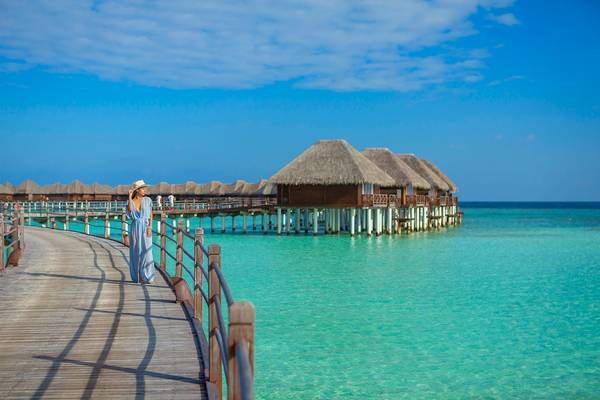 Eine Frau am Holzsteg vor dem Sun Siyam Vilu Reef Hotel
