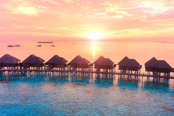 Sonnenuntergang am Sun Siyam Vilu Reef mit Blick auf Wasservillen und Boote