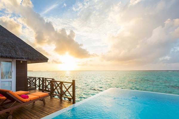 Sonnenuntergang am Pool des Sun Siyam Vilu Reef Hotels mit Blick auf das Meer.