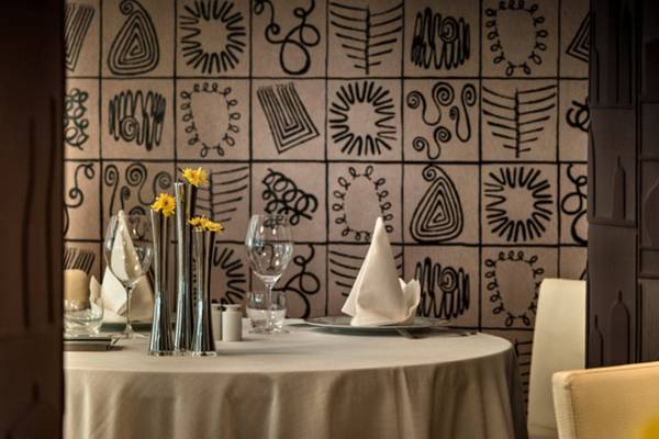 Innenansicht des Grand Hotel Resort Ma&Ma mit einem gedeckten Tisch und abstrakten Wandmalereien.