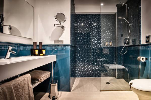 Badezimmer im Grand Hotel Resort Ma&Ma mit blauen Fliesen und moderner Dusche.