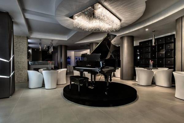 Lobby des Grand Hotel Resort Ma&Ma mit Klavier, weißen Stühlen und Kristallleuchter.