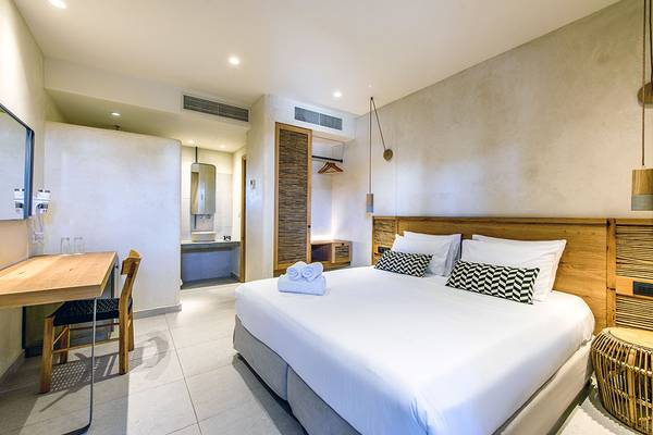 Ein modernes Schlafzimmer im Stella Village Hotel mit einem großen Bett, Holzmöbeln und einem Schreibtisch.