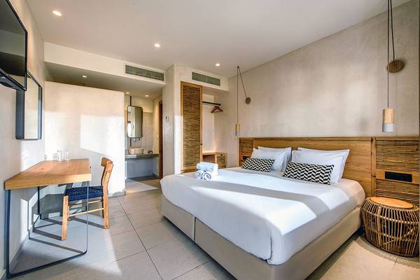 Innenansicht eines Zimmers im Stella Village Hotel & Bungalows mit Bett, Schreibtisch und Stuhl.