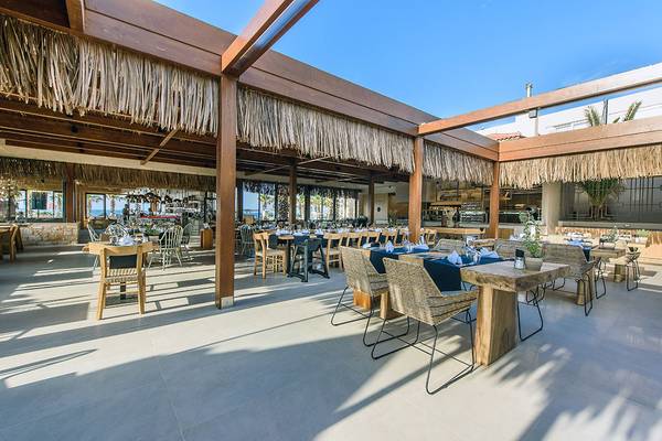 Restaurant im Stella Village Hotel & Bungalows mit Tisch, Stühlen und Holzdach.