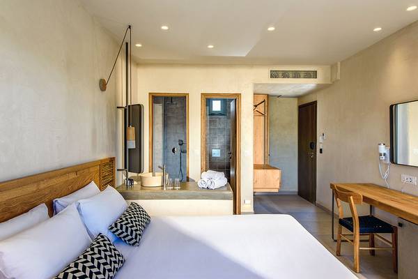 Innenansicht eines Badezimmers im Stella Village Hotel & Bungalows mit Bett, Waschbecken und Dusche.