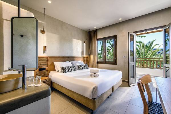 Schlafzimmer im Stella Village Hotel mit Balkon, Bett, Tisch und Blick auf Palmen