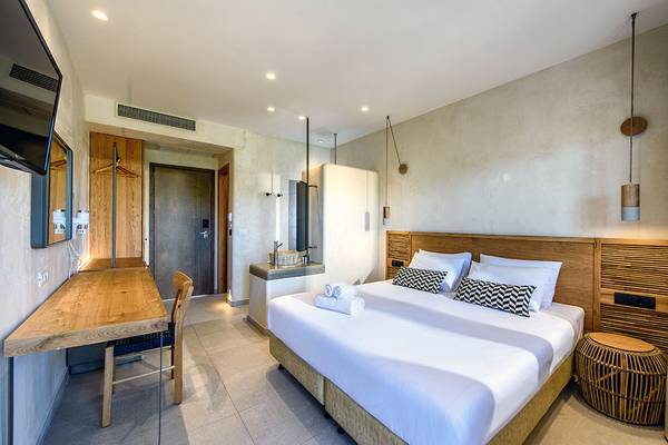 Innenansicht eines Zimmers im Stella Village Hotel & Bungalows mit Bett, Schreibtisch und Badezimmer