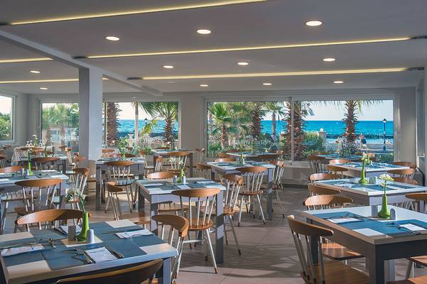 Innenansicht des Restaurants im Stella Village Hotel mit Blick auf den Ozean.