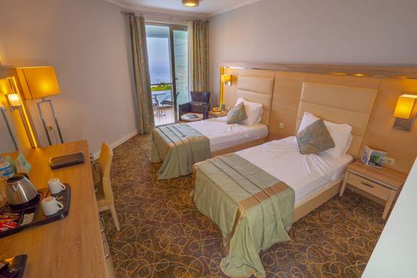 Doppelzimmer im Grand Belish Resort Hotel & Spa mit zwei Betten, Schreibtisch und Balkonzugang.