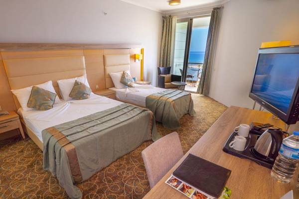 Doppelzimmer im Grand Belish Resort Hotel mit Meerblick, zwei Betten, Schreibtisch und Fernseher.