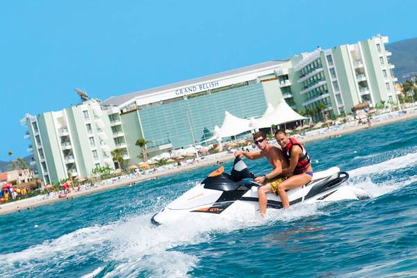 Zwei Leute auf Jet Ski vor dem Grand Belish Hotel