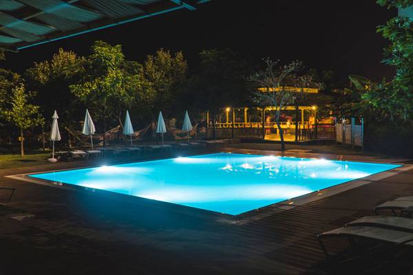 Der Außenpool des Grand Belish Resort Hotels bei Nacht, mit blauem Licht und Lounge-Stühlen.