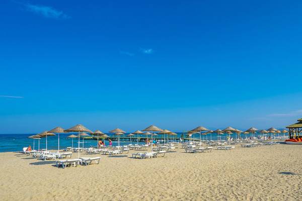 Strand des Grand Belish Resort Hotel & Spa mit Sonnenschirmen und Liegestühlen