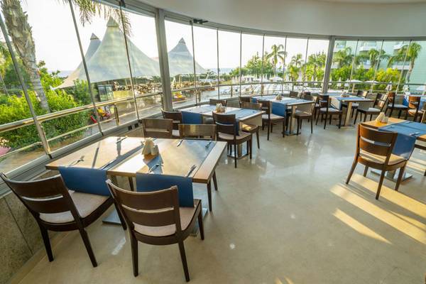 Innenansicht des Restaurants im Grand Belish Resort Hotel & Spa mit runden Tischen und Stühlen.