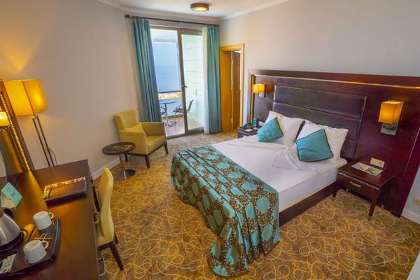 Schlafzimmer im Grand Belish Resort Hotel & Spa mit Bett, Nachttischen, Sessel und Balkon