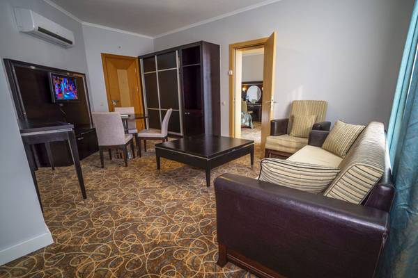 Wohnzimmer im Grand Belish Resort Hotel & Spa mit Sofa, Tisch, Fernseher und Esstisch.