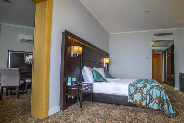 Schlafzimmer im Grand Belish Resort Hotel & Spa mit einem Bett, Kissen und einer Lampe.