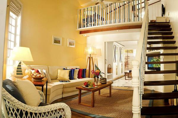 Innenansicht des Wohnbereichs im Centara Grand Island Resort & Spa mit Sofa, Tisch, Lampe und Treppe.