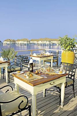 Terrasse mit Tischen im Centara Grand Island Resort & Spa, umgeben von Wasser und Pflanzen