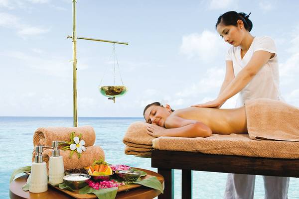 Eine Frau genießt eine Massage am Strand im Centara Grand Island Resort & Spa.