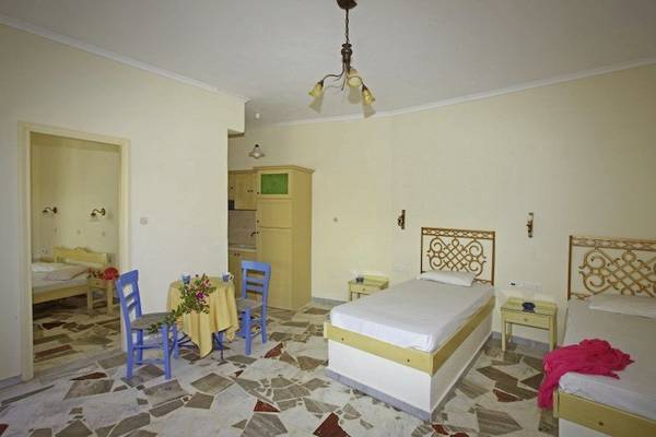 Ein Schlafzimmer im Corissia Beach Hotel mit zwei Betten, gelben Stühlen und einem Tisch.