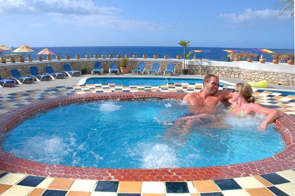 Ein Paar genießt das Schwimmbad im Samsara Cliff Resort mit Blick auf das Meer.