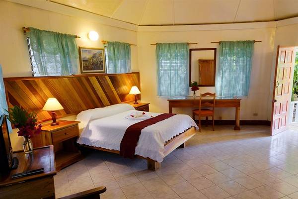 Schlafzimmer im Samsara Cliff Resort mit Bett, Schreibtisch und Pflanzen.