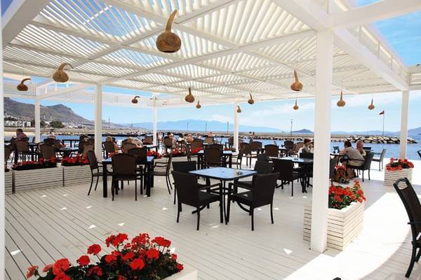 Terrasse des La Blanche Resort & Spa mit Tischen und Stühlen, Blick auf das Meer.