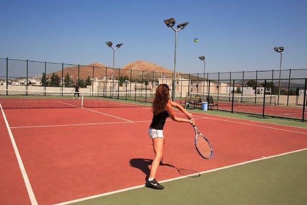 Tennisplatz im La Blanche Resort & Spa mit einer Spielerin, die einen Ball schlägt.