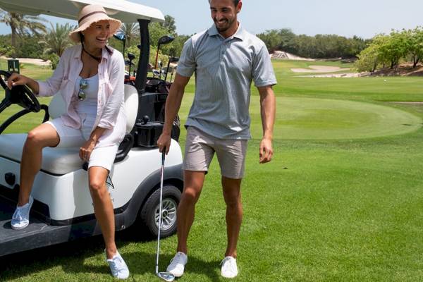 Ein Paar steht neben einem Golfwagen auf dem JA Lake View Hotel Golfplatz.
