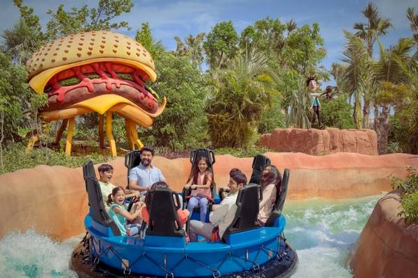 Familie im Ja Lake View Hotel auf einer blauen Wasserrutsche, mit einem riesigen Hamburger im Hintergrund.