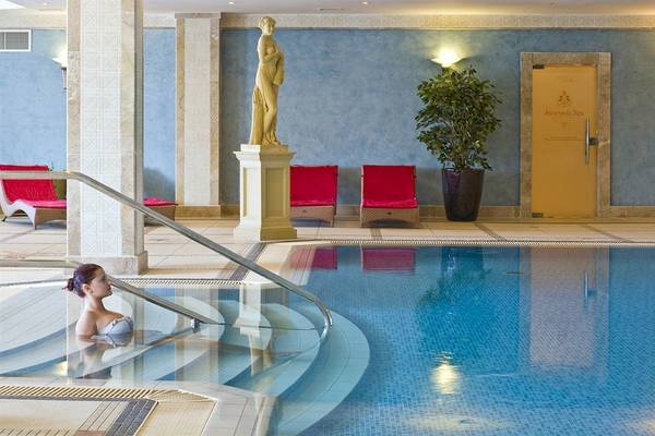 Ein Swimmingpool mit einer Frau im Wasser, umgeben von roten Stühlen und einer Statue.