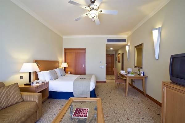 Hotelzimmer im Radisson Blu Resort & Spa, Malta Golden Sands mit Doppelbett, Schreibtisch und Fernseher.