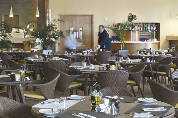 Restaurant im Radisson Blu Resort & Spa, Malta Golden Sands mit gedeckten Tischen und einem Kellner.