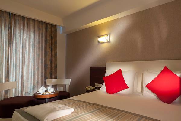Hotelzimmer im Seher Resort & Spa mit einem Bett, roten Kissen und einem Tisch.