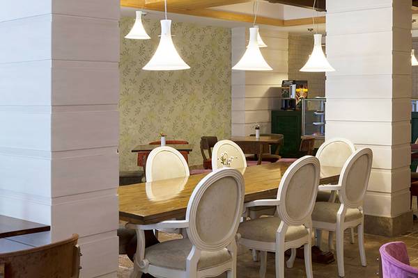 Innenbereich des Restaurants des Seher Resort & Spa mit langen Holztischen und weißen Stühlen.