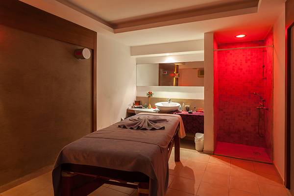Massageraum im Seher Resort & Spa mit Tisch, Bett, rotem Licht und Dusche