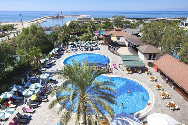 Luftaufnahme des Seher Resort & Spa mit Swimmingpool, Sonnenliegen, Gästen und Blick aufs Meer.