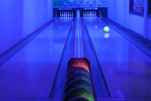Bowlingbahn im Seher Resort & Spa mit blauer Beleuchtung und Bowlingkugeln