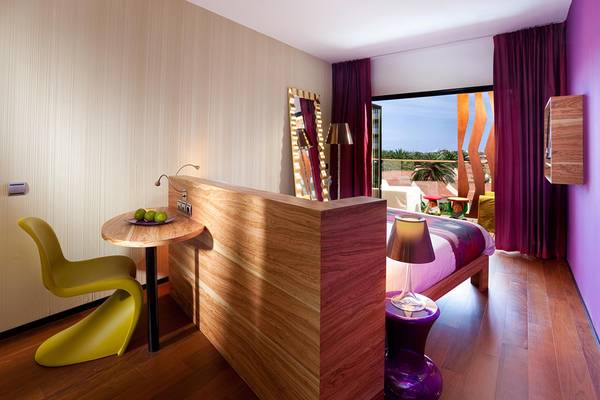 Innenansicht eines Zimmers im Bohemia Suites & Spa mit modernem Design, einem Bett, Schreibtisch und offenem Balkon.