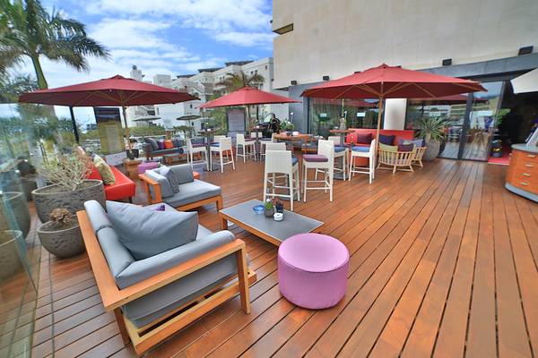 Terrasse des Bohemia Suites & Spa mit Möbeln, Tischen, Stühlen und roten Sonnenschirmen.
