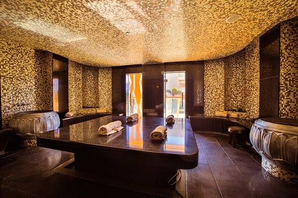 Saunaraum im Bohemia Suites & Spa mit goldenen Fliesen und gerollten Handtüchern auf einem Tisch.
