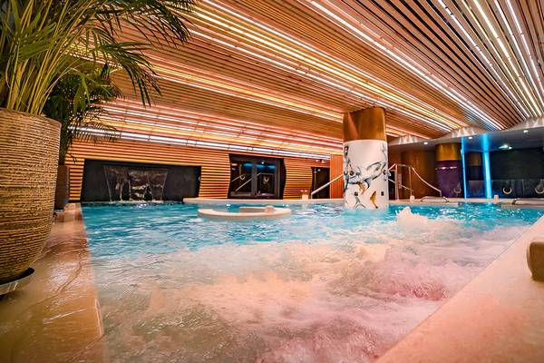 Innenpool des Bohemia Suites & Spa mit Wasserfontänen und hölzerne Decke.