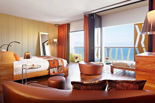 Ein modernes Hotelzimmer mit Meerblick im Bohemia Suites & Spa, mit einem großen Bett, Sofa, Tisch und einem Balkon.
