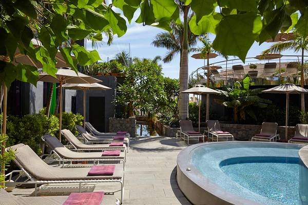 Pool-Lounge-Bereich im Garten des Bohemia Suites & Spa mit Liegestühlen und Sonnenschirmen.