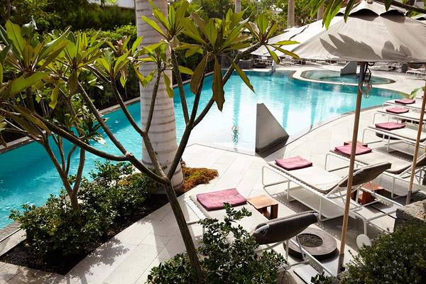 Außenbereich eines Hotels mit einem Pool, Liegestühlen und Sonnenschirmen.