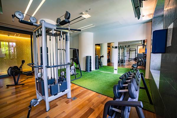 Fitnessstudio im Hotel Bohemia Suites & Spa mit modernen Geräten und grünem Teppichboden.