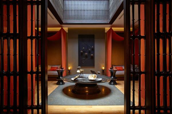 Innenansicht des Spa-Bereichs im Bohemia Suites & Spa mit einem zentralen Tisch, Kerzen und roten Vorhängen.