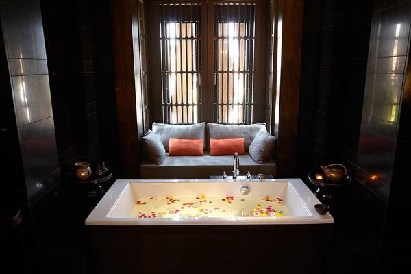 Ein Badezimmer mit einer Badewanne gefüllt mit Blumen und einem Sofa neben einem Fenster.